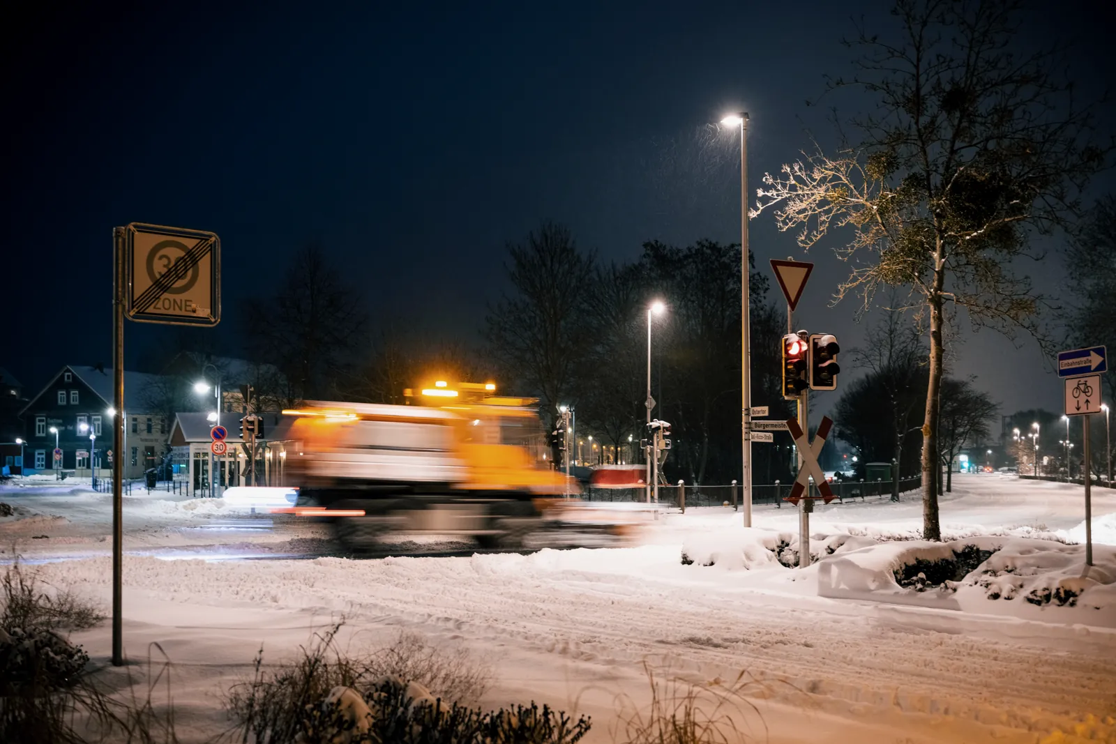 Winterdienst-Räumfahrzeug nachts auf verschneiter Straße